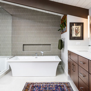 Idee per una stanza da bagno padronale moderna di medie dimensioni con ante lisce, ante in legno bruno, vasca freestanding, doccia ad angolo, WC monopezzo, piastrelle grigie, piastrelle di vetro, pareti grigie, pavimento in gres porcellanato, lavabo sottopiano, top in quarzo composito, pavimento bianco, porta doccia a battente, top bianco, due lavabi, mobile bagno sospeso e travi a vista