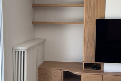 Aménagement d'un petit salon moderne avec une bibliothèque ou un coin lecture, un mur blanc, parquet clair, un téléviseur fixé au mur et un sol beige.