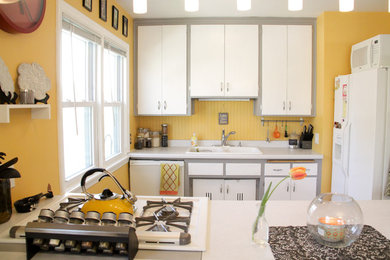 Example of an eclectic u-shaped kitchen design in Minneapolis with white cabinets, a drop-in sink and white appliances