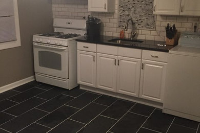 Inspiration for a small timeless galley slate floor enclosed kitchen remodel in Baltimore with an undermount sink, recessed-panel cabinets, white cabinets, granite countertops, white backsplash, ceramic backsplash, white appliances and no island