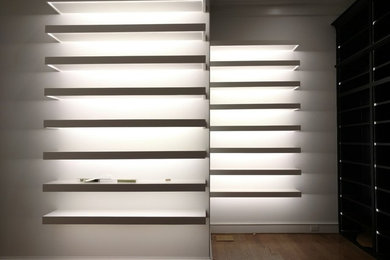Photo of a medium sized traditional walk-in wardrobe for men in Houston with white cabinets and light hardwood flooring.