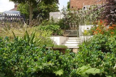 Medium sized contemporary back full sun garden for summer in Sussex with a retaining wall and natural stone paving.