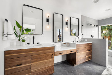 Double shower - contemporary master subway tile gray floor and double-sink double shower idea in San Francisco with flat-panel cabinets, medium tone wood cabinets, an undermount sink, a hinged shower door, white countertops and a built-in vanity