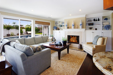 Beach style enclosed medium tone wood floor family room library photo in Orange County with beige walls, a standard fireplace, a tile fireplace and no tv