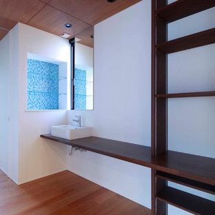 Photo of a large modern home office and library in Other with white walls, plywood flooring, a built-in desk, brown floors and a reading nook.