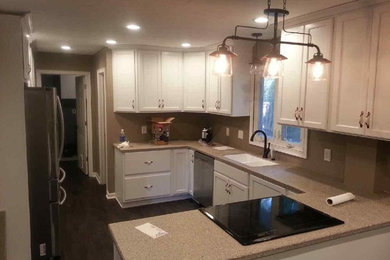 Inspiration for a mid-sized timeless u-shaped dark wood floor enclosed kitchen remodel in Chicago with an integrated sink, shaker cabinets, white cabinets, solid surface countertops, stainless steel appliances and a peninsula