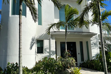 Modelo de fachada de casa blanca y negra costera grande de dos plantas con revestimiento de estuco, tejado plano y tejado de metal