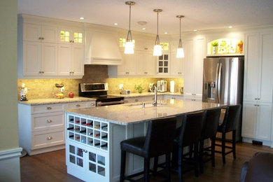 Inspiration for a mid-sized timeless l-shaped medium tone wood floor eat-in kitchen remodel in Calgary with an undermount sink, shaker cabinets, white cabinets, granite countertops, beige backsplash, stone tile backsplash, stainless steel appliances and an island