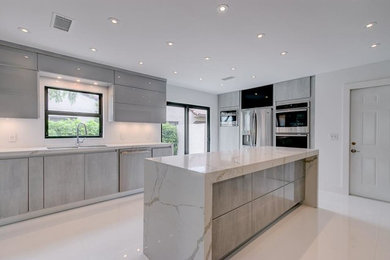 Mid-sized minimalist single-wall concrete floor and white floor enclosed kitchen photo in Miami with a double-bowl sink, flat-panel cabinets, gray cabinets, marble countertops, stainless steel appliances, an island and gray countertops