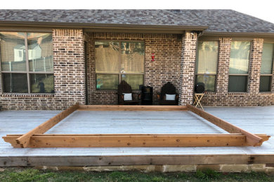 Example of a mid-sized minimalist backyard ground level deck design in Dallas with a pergola
