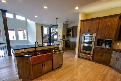 Example of a mid-sized transitional u-shaped light wood floor eat-in kitchen design in Other with a farmhouse sink, flat-panel cabinets, dark wood cabinets, solid surface countertops, yellow backsplash, subway tile backsplash, stainless steel appliances and no island