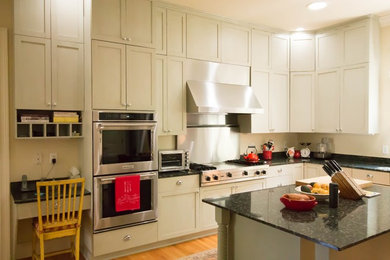 Example of a large classic u-shaped light wood floor eat-in kitchen design in Raleigh with shaker cabinets, granite countertops, an island and multicolored countertops