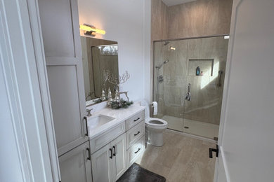 Example of a large transitional 3/4 beige tile and porcelain tile porcelain tile, beige floor and single-sink alcove shower design in Chicago with recessed-panel cabinets, white cabinets, a two-piece toilet, white walls, an undermount sink, quartz countertops, a hinged shower door, white countertops, a niche and a built-in vanity