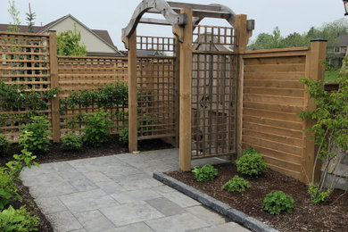 This is an example of a mid-sized contemporary backyard concrete paver and wood fence garden path in Toronto.