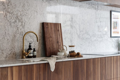 Ispirazione per una cucina minimalista di medie dimensioni con ante lisce, ante in legno bruno, top in quarzite, elettrodomestici da incasso e nessuna isola