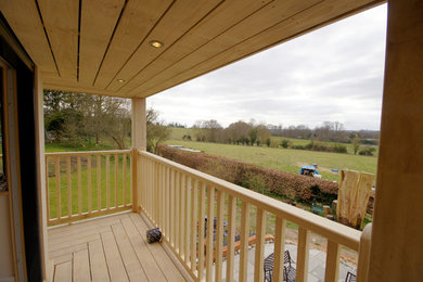 This is an example of a large country wood railing balcony in Dorset with a roof extension.
