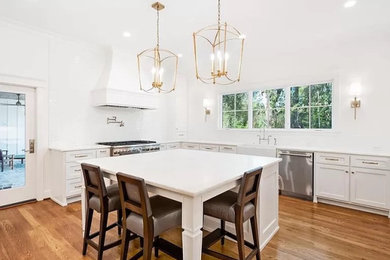 Example of a large classic medium tone wood floor and brown floor kitchen design in Other with a farmhouse sink, shaker cabinets, white cabinets, marble countertops, ceramic backsplash, stainless steel appliances and white countertops