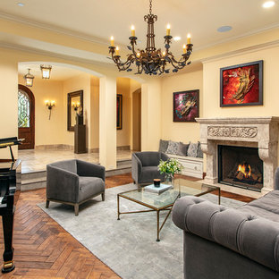 Ejemplo de salón abierto, mediterráneo, con paredes amarillas, suelo de madera oscura, chimenea tradicional y suelo marrón