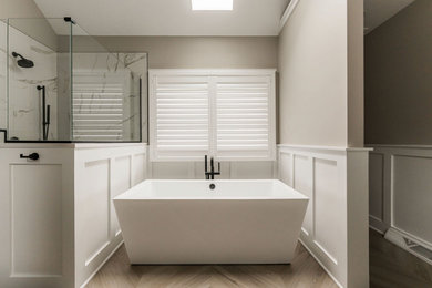 Example of a large transitional master ceramic tile, brown floor, double-sink, vaulted ceiling and wainscoting bathroom design in Chicago with recessed-panel cabinets, black cabinets, a two-piece toilet, gray walls, an undermount sink, quartzite countertops, a hinged shower door, white countertops and a built-in vanity