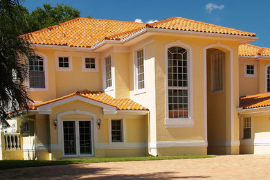 Inspiration for a mid-sized mediterranean two-storey stucco yellow house exterior in Orlando with a hip roof and a tile roof.