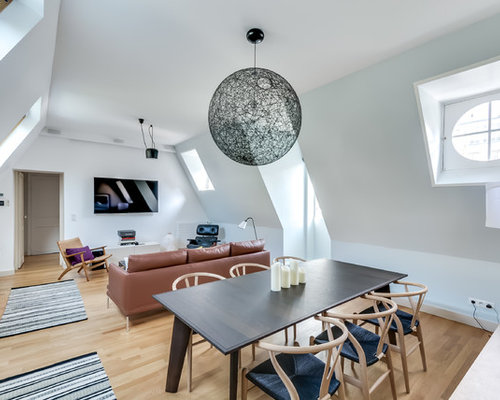 Cette image montre une salle à manger ouverte sur le salon design de taille moyenne avec un mur blanc, un sol en bois brun et aucune cheminée.