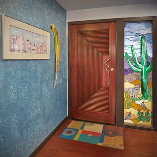 Inspiration pour une porte d'entrée bohème avec un mur bleu, un sol en bois brun, une porte simple, une porte en bois brun et un sol marron.
