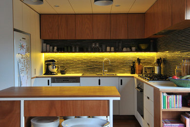 Example of a small trendy l-shaped medium tone wood floor kitchen design in Auckland with flat-panel cabinets, white cabinets, ceramic backsplash and black backsplash