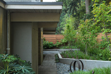 This is an example of a small mid-century modern drought-tolerant and partial sun backyard wood fence retaining wall landscape in Portland for winter.