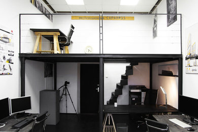 Ejemplo de despacho industrial pequeño con paredes blancas, suelo de madera pintada y escritorio independiente