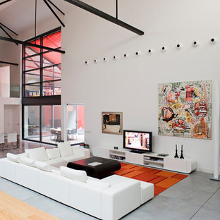 Foto de sala de estar abierta, urbana, con paredes blancas, suelo de cemento, televisor independiente y suelo gris