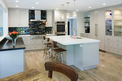 Transitional ceramic tile kitchen photo in Cleveland with a single-bowl sink, recessed-panel cabinets, gray cabinets, quartz countertops, metallic backsplash, cement tile backsplash, white appliances and an island