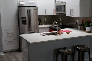 Inspiration for a mid-sized contemporary u-shaped vinyl floor and gray floor eat-in kitchen remodel in Calgary with an undermount sink, flat-panel cabinets, white cabinets, quartzite countertops, beige backsplash, porcelain backsplash, stainless steel appliances and a peninsula