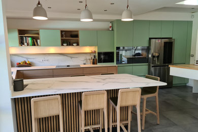 Réalisation d'une grande cuisine ouverte design en U et bois clair avec un plan de travail en surface solide, un sol en carrelage de céramique et un sol gris.
