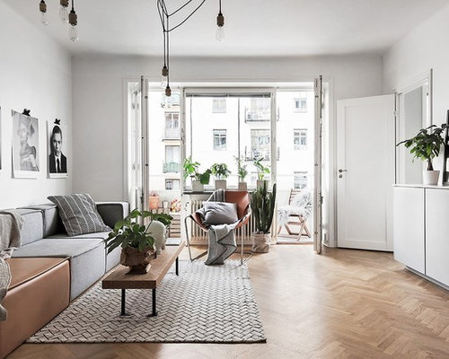 Bild på ett mellanstort nordiskt allrum med öppen planlösning, med vita väggar och mellanmörkt trägolv