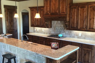 Large elegant l-shaped travertine floor eat-in kitchen photo in Dallas with dark wood cabinets, granite countertops, an island, an undermount sink, raised-panel cabinets, beige backsplash, ceramic backsplash and stainless steel appliances