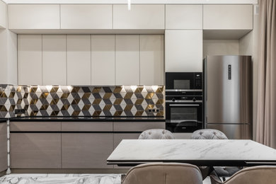This is an example of a mid-sized contemporary l-shaped open plan kitchen in Saint Petersburg with an undermount sink, flat-panel cabinets, beige cabinets, quartz benchtops, multi-coloured splashback, mosaic tile splashback, black appliances, ceramic floors, white floor and black benchtop.