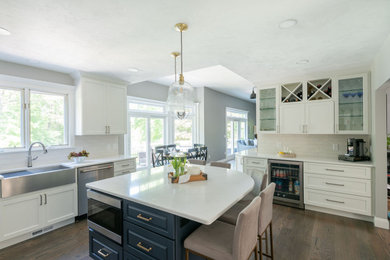 Huge transitional u-shaped medium tone wood floor and brown floor eat-in kitchen photo in Boston with a farmhouse sink, shaker cabinets, white cabinets, quartz countertops, white backsplash, ceramic backsplash, stainless steel appliances and white countertops