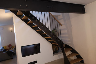 Cette image montre un grand escalier courbe urbain avec des marches en bois, un garde-corps en matériaux mixtes et palier.