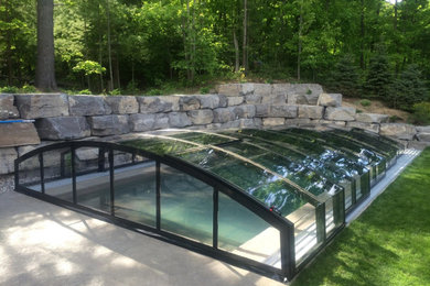 Pool house - mid-sized backyard stamped concrete and rectangular infinity pool house idea in Toronto