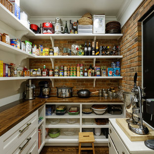 Aménagement d'une arrière-cuisine classique en L avec des portes de placard blanches, un plan de travail en bois, une crédence en brique, un sol en bois foncé, un sol marron et un plan de travail marron.