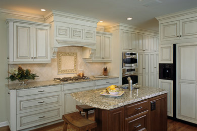 Example of a large classic u-shaped medium tone wood floor eat-in kitchen design in Other with raised-panel cabinets and an island