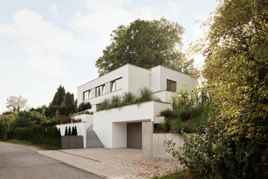Großes, Dreistöckiges Modernes Haus mit Putzfassade, weißer Fassadenfarbe, Flachdach, grauem Dach und Wandpaneelen in München