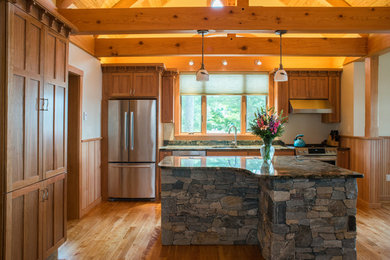 Photo of a large arts and crafts single-wall eat-in kitchen in Portland Maine with a drop-in sink, shaker cabinets, medium wood cabinets, granite benchtops, stainless steel appliances, light hardwood floors and with island.