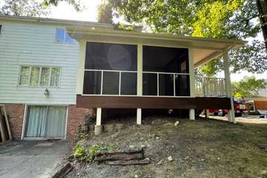 This is an example of a mid-sized screened-in back porch design in Other.