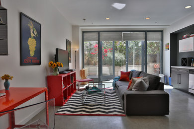 Small industrial open concept family room in San Luis Obispo with white walls, concrete floors and a freestanding tv.