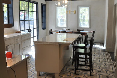 This is an example of a large traditional l-shaped eat-in kitchen in New York with a drop-in sink, flat-panel cabinets, white cabinets, laminate benchtops, white splashback, ceramic splashback, stainless steel appliances, ceramic floors, with island, multi-coloured floor and white benchtop.