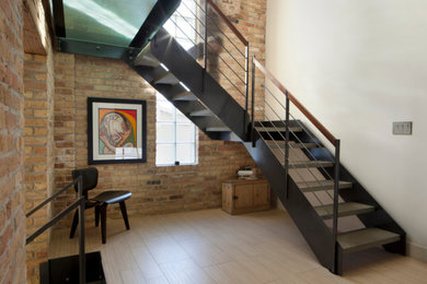 シカゴにある中くらいなインダストリアルスタイルのおしゃれなかね折れ階段 (金属の手すり、レンガ壁) の写真