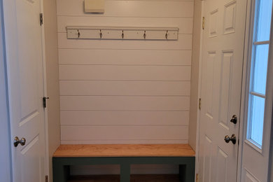 Example of a mid-sized light wood floor and shiplap wall entryway design in Other with gray walls and a white front door