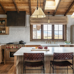 Diseño de cocina en L, rústica, con fregadero sobremueble, armarios abiertos, puertas de armario de madera oscura, salpicadero blanco, electrodomésticos de acero inoxidable, suelo de madera en tonos medios, una isla y encimeras blancas