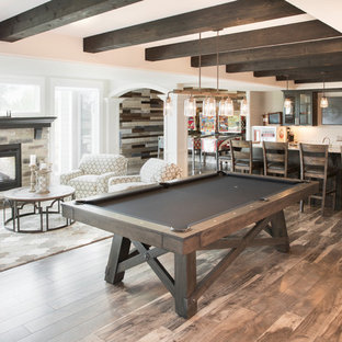 Photo of a large classic walk-out basement in Milwaukee with beige walls, medium hardwood flooring, a two-sided fireplace, a stone fireplace surround and brown floors.
